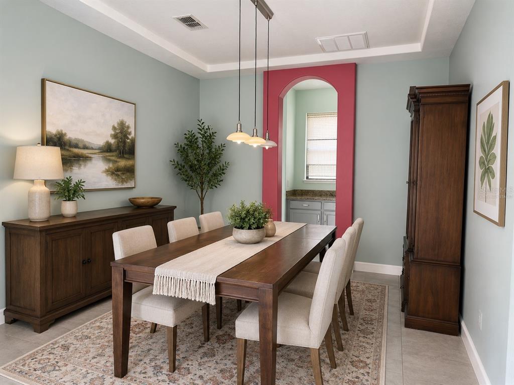 A dining room features a wooden table, upholstered chairs, a sideboard, and a pink arched doorway — 10068 SILVER LAUREL WAY, ORLANDO, FL
