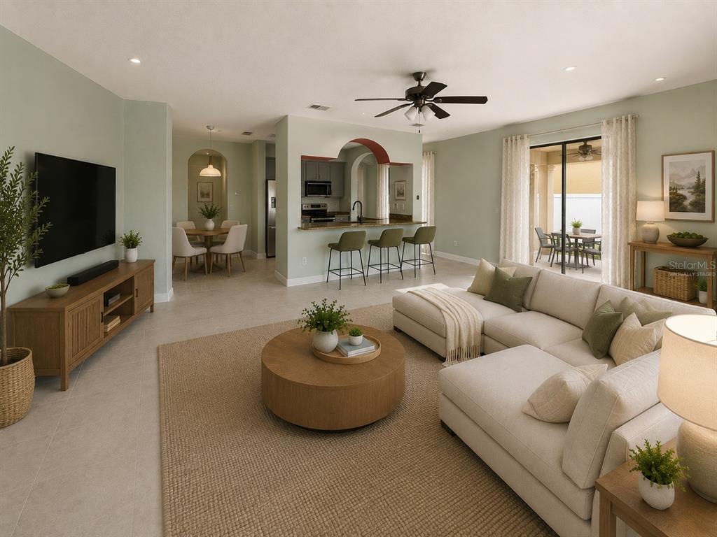 A living room with a sectional sofa, round coffee table, and an open kitchen area — 10068 SILVER LAUREL WAY, ORLANDO, FL