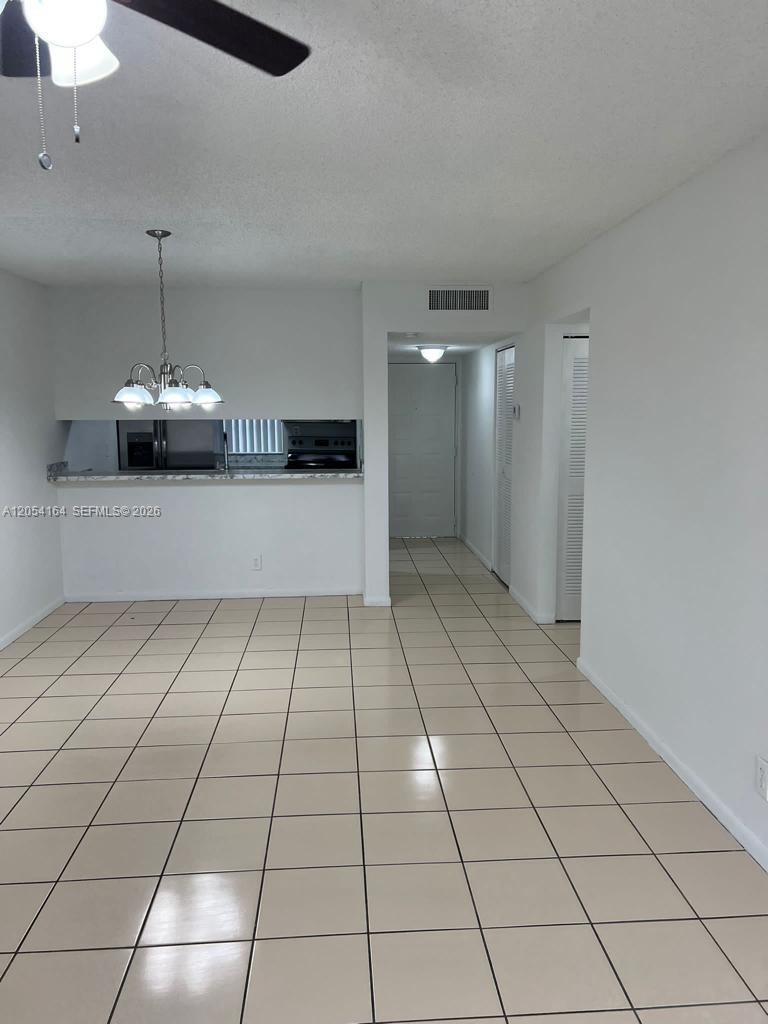 A dining area with light-colored floor tiles leads to a kitchen pass-through and hallway — 8720 N Sherman Cir # 303, Miramar FL 33025, MIRAMAR, FL
