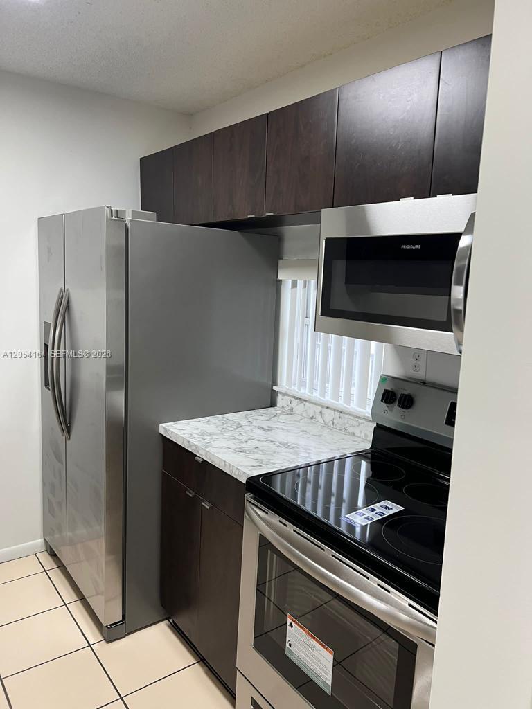 A kitchen features stainless steel appliances, dark wood cabinets, and a white marble-patterned countertop — 8720 N Sherman Cir # 303, Miramar FL 33025, MIRAMAR, FL