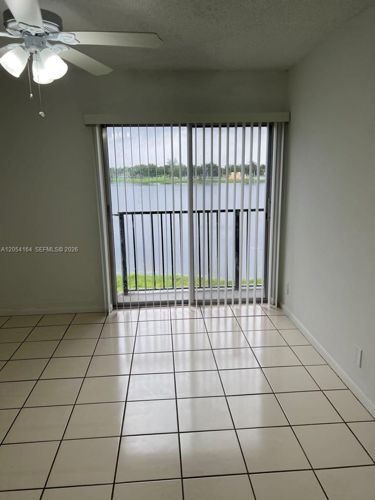 An empty room with white tile floors, a ceiling fan, and sliding doors to a balcony — 8720 N Sherman Cir # 303, Miramar FL 33025, MIRAMAR, FL