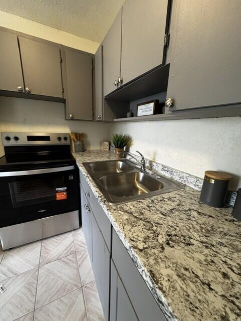A kitchen features grey cabinets, a stainless steel stove, and a speckled granite countertop — 116 N F Street # 7, FL 33460, FL
