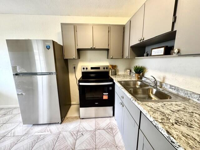 A kitchen features stainless steel appliances, gray cabinets, and granite-look countertops over tiled flooring — 116 N F Street # 7, FL 33460, FL