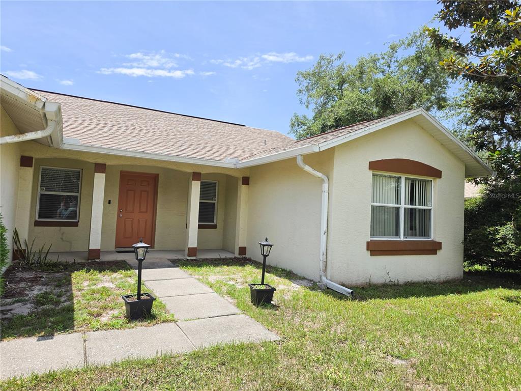 A single-story house with a tan stucco exterior, brown trim, and a concrete walkway — 29 FREEMONT TURN, PALM COAST, FL