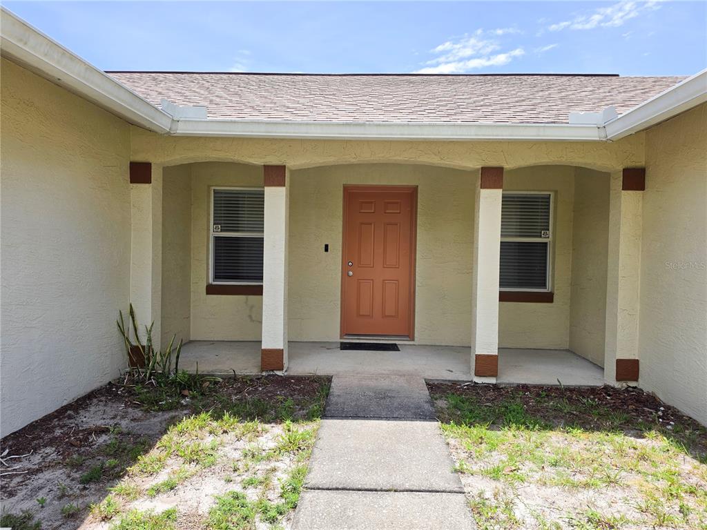 The exterior of a house features a tan stucco facade, a brown door, and a walkway — 29 FREEMONT TURN, PALM COAST, FL