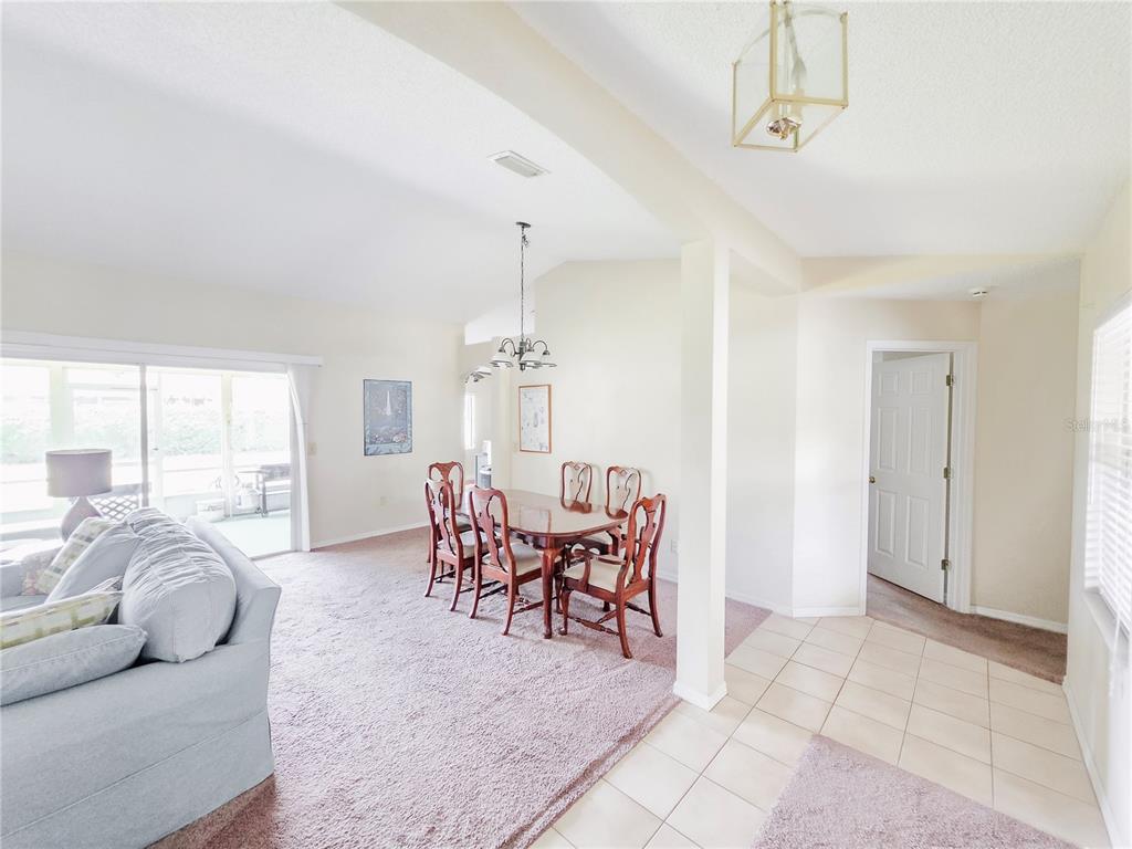 A dining area with a wooden table and chairs sits adjacent to a carpeted living space — 29 FREEMONT TURN, PALM COAST, FL