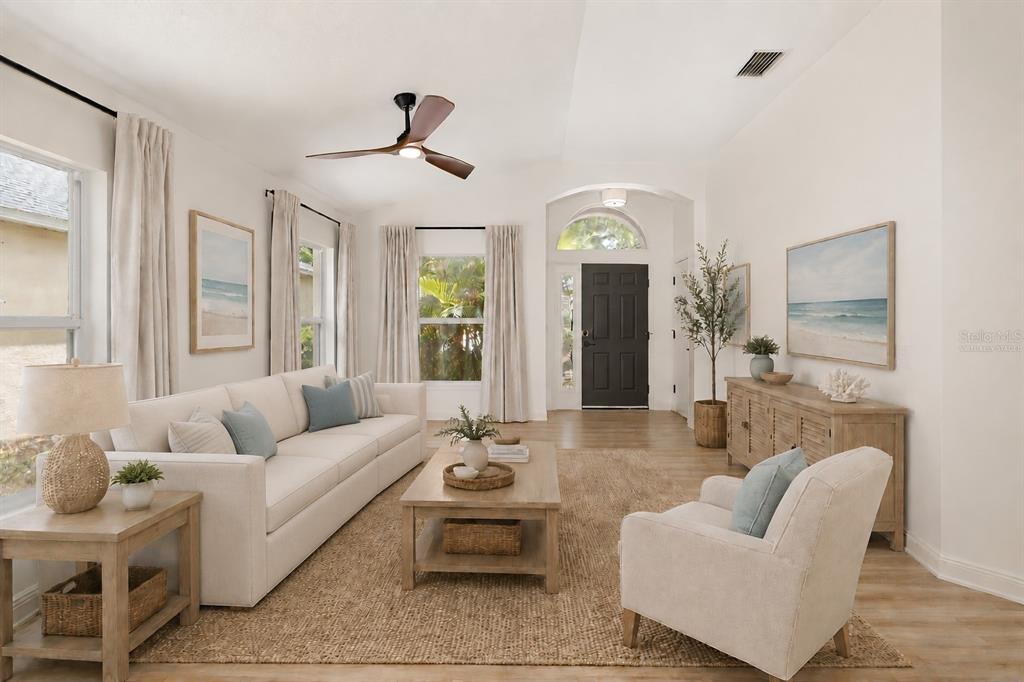 A bright living room features a beige sofa, wooden coffee table, and a dark front door — 6226 BLUEFLOWER COURT, LAKEWOOD RANCH, FL