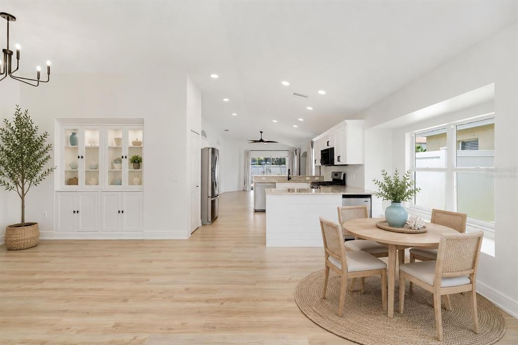 An open-concept kitchen and dining area features white cabinetry, light wood flooring, and recessed lighting — 6226 BLUEFLOWER COURT, LAKEWOOD RANCH, FL
