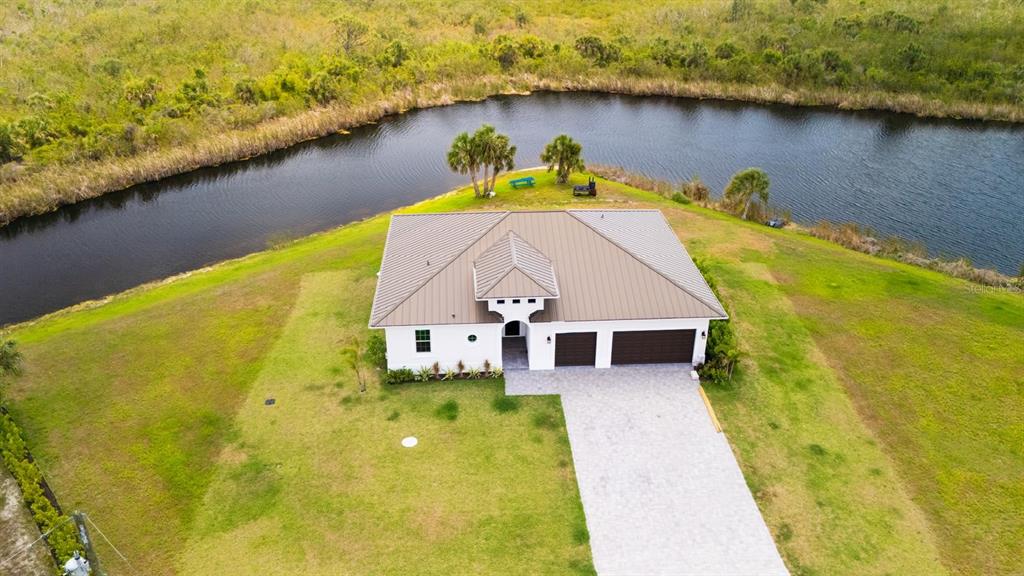 An aerial view shows a single-story house with a metal roof beside a canal — 12116 SEA-ROBIN LANE, PLACIDA, FL