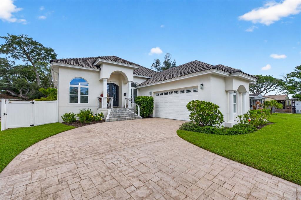A single-story house with a white stucco exterior, tiled roof, and a paved driveway — 815 59TH AVENUE NE, ST PETERSBURG, FL