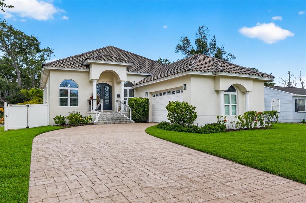 A single-story house with a tiled roof, arched windows, and a paved driveway — 815 59TH AVENUE NE, ST PETERSBURG, FL