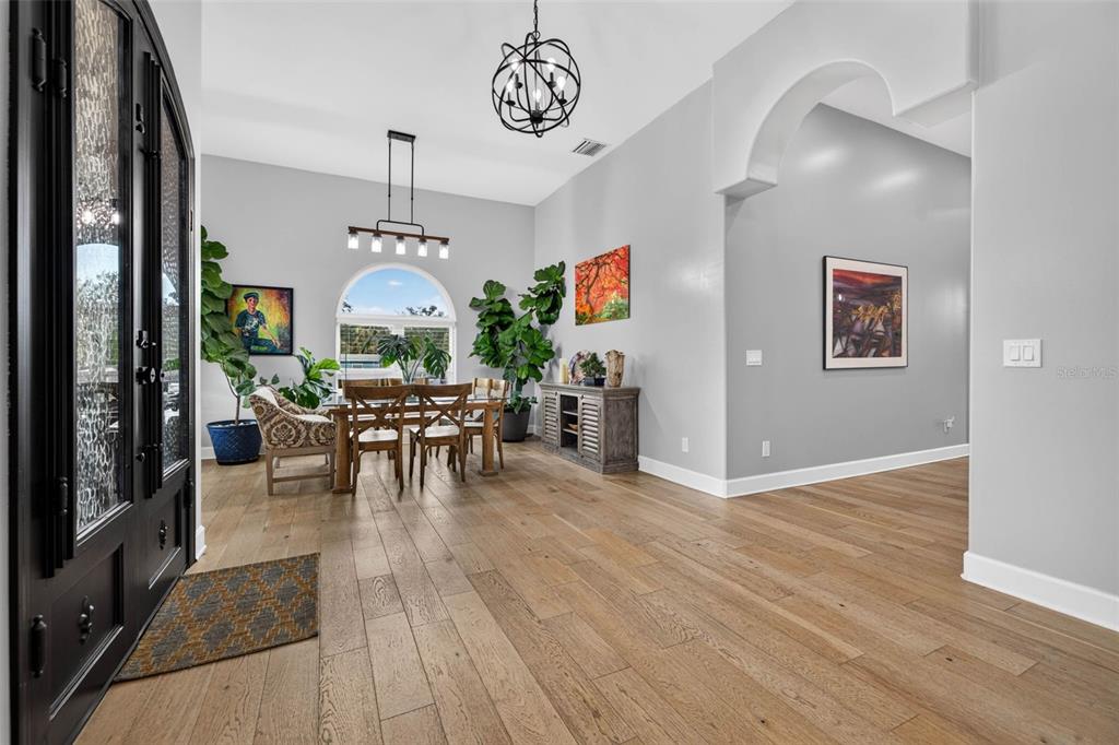 A dining area with wood floors, a large arched window, and a modern chandelier — 815 59TH AVENUE NE, ST PETERSBURG, FL