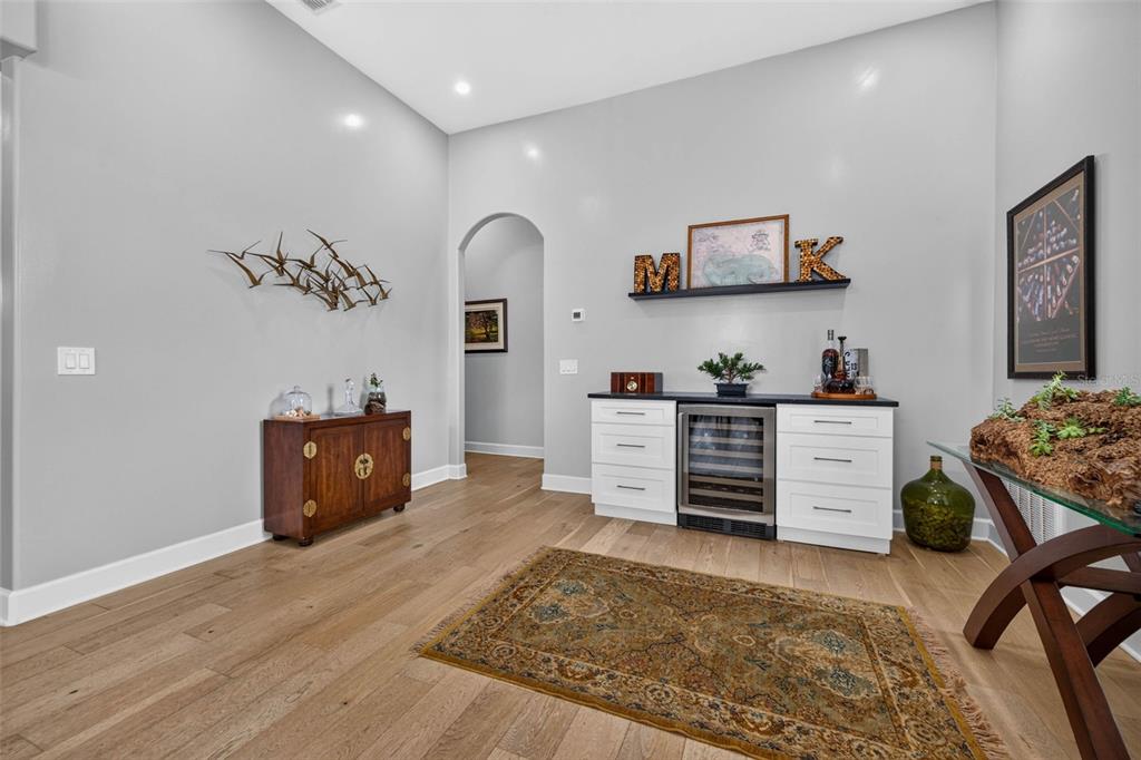 A room with light wood flooring, a wine cooler, white cabinetry, and a patterned area rug — 815 59TH AVENUE NE, ST PETERSBURG, FL