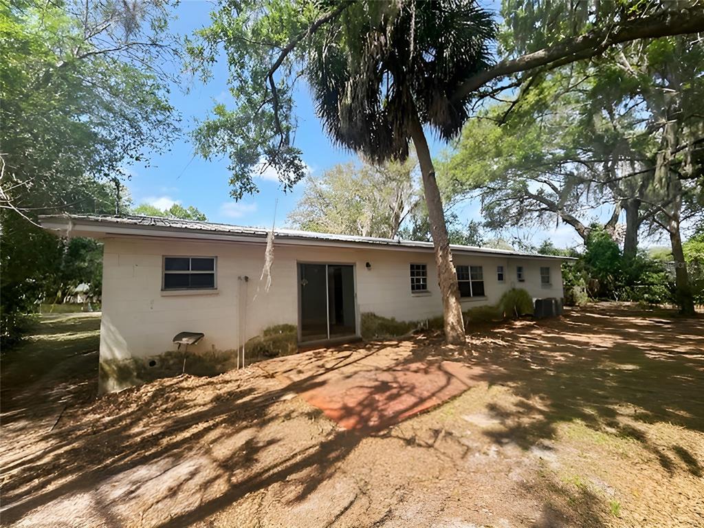 The exterior of a single-story white house features a sliding glass door and a patio — 23 NE 6TH STREET, CHIEFLAND, FL