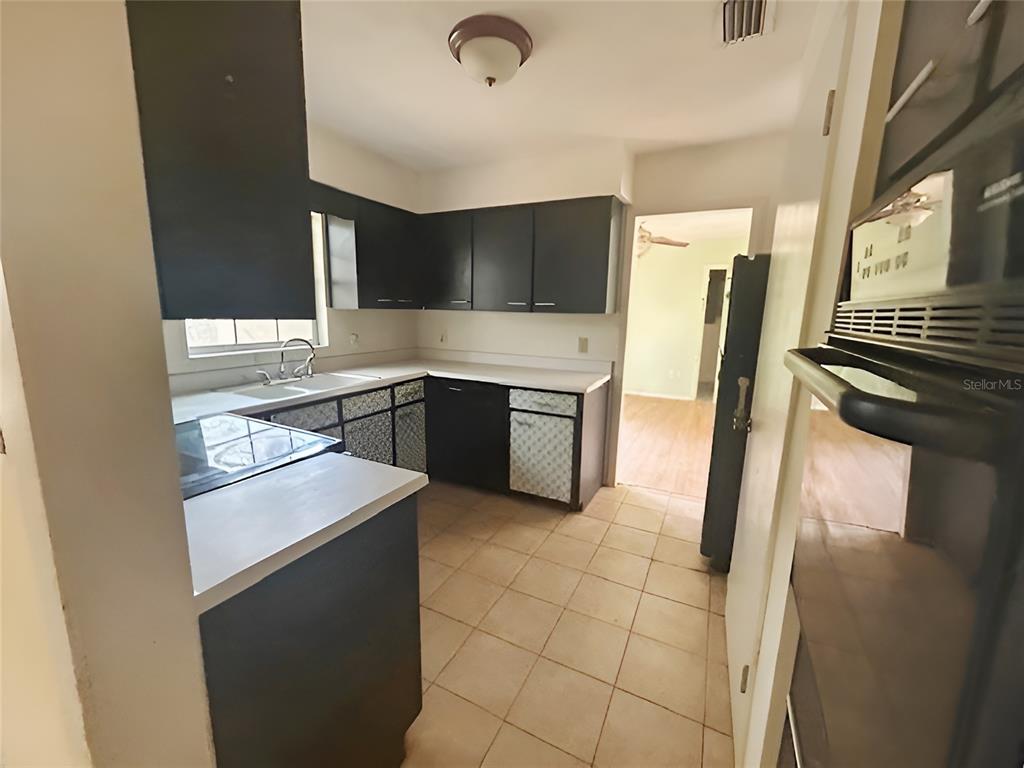 A kitchen features dark cabinets, white countertops, tiled flooring, and a built-in wall oven — 23 NE 6TH STREET, CHIEFLAND, FL