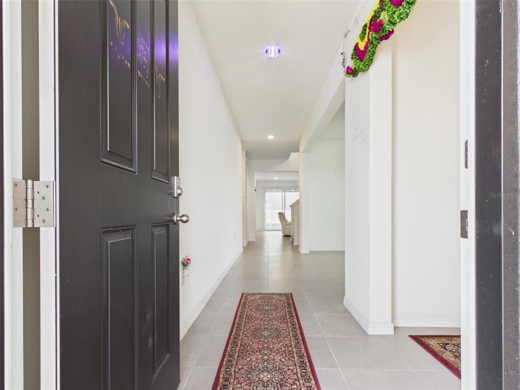 A view through an open front door into a tiled hallway with a runner rug — 5962 SW 80TH LN, OCALA, FL