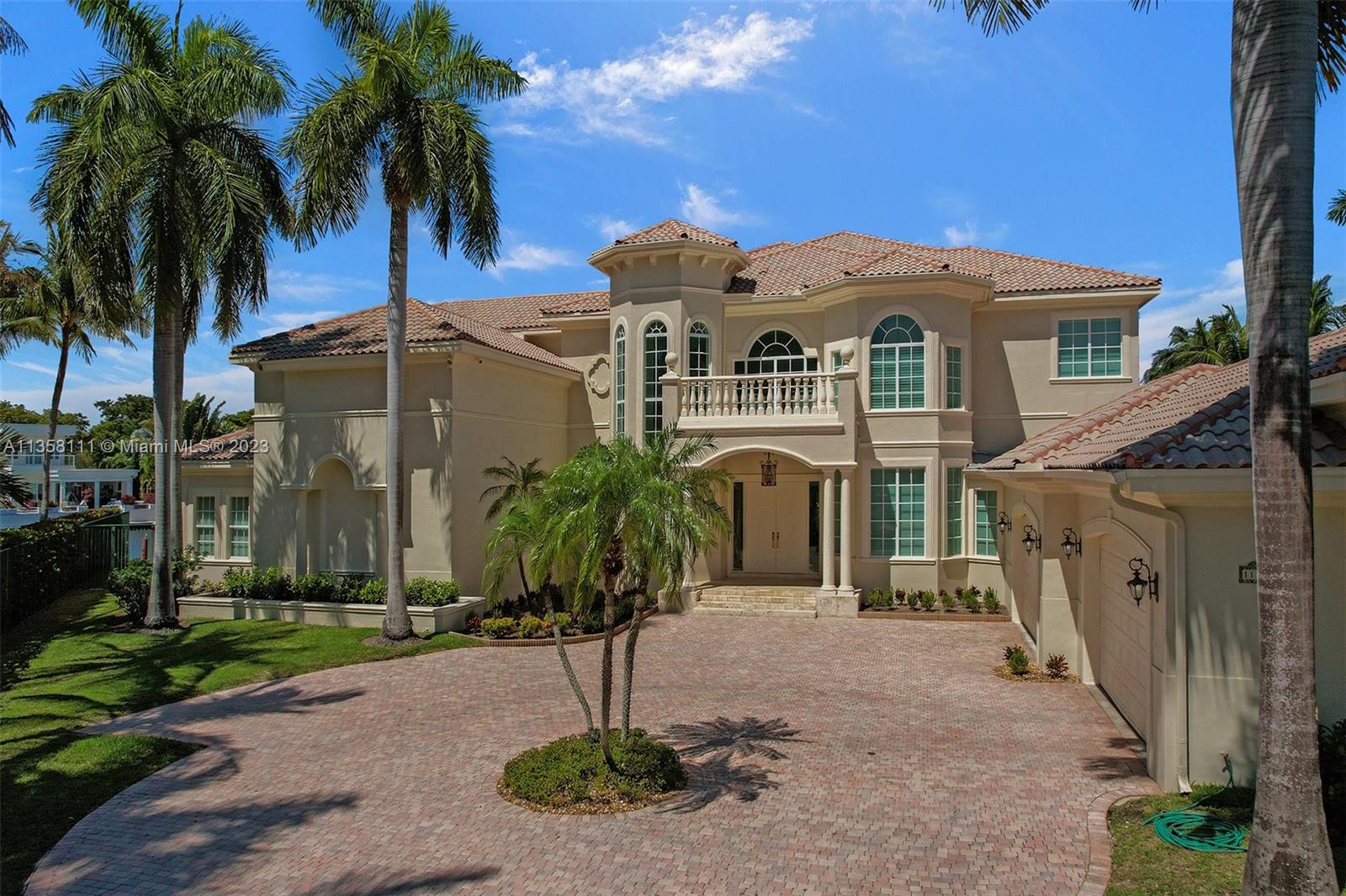 A two-story Mediterranean-style house features a brick driveway, palm trees, and a tiled roof — 1130 Harbor Ct, Hollywood FL 33019, HOLLYWOOD, FL