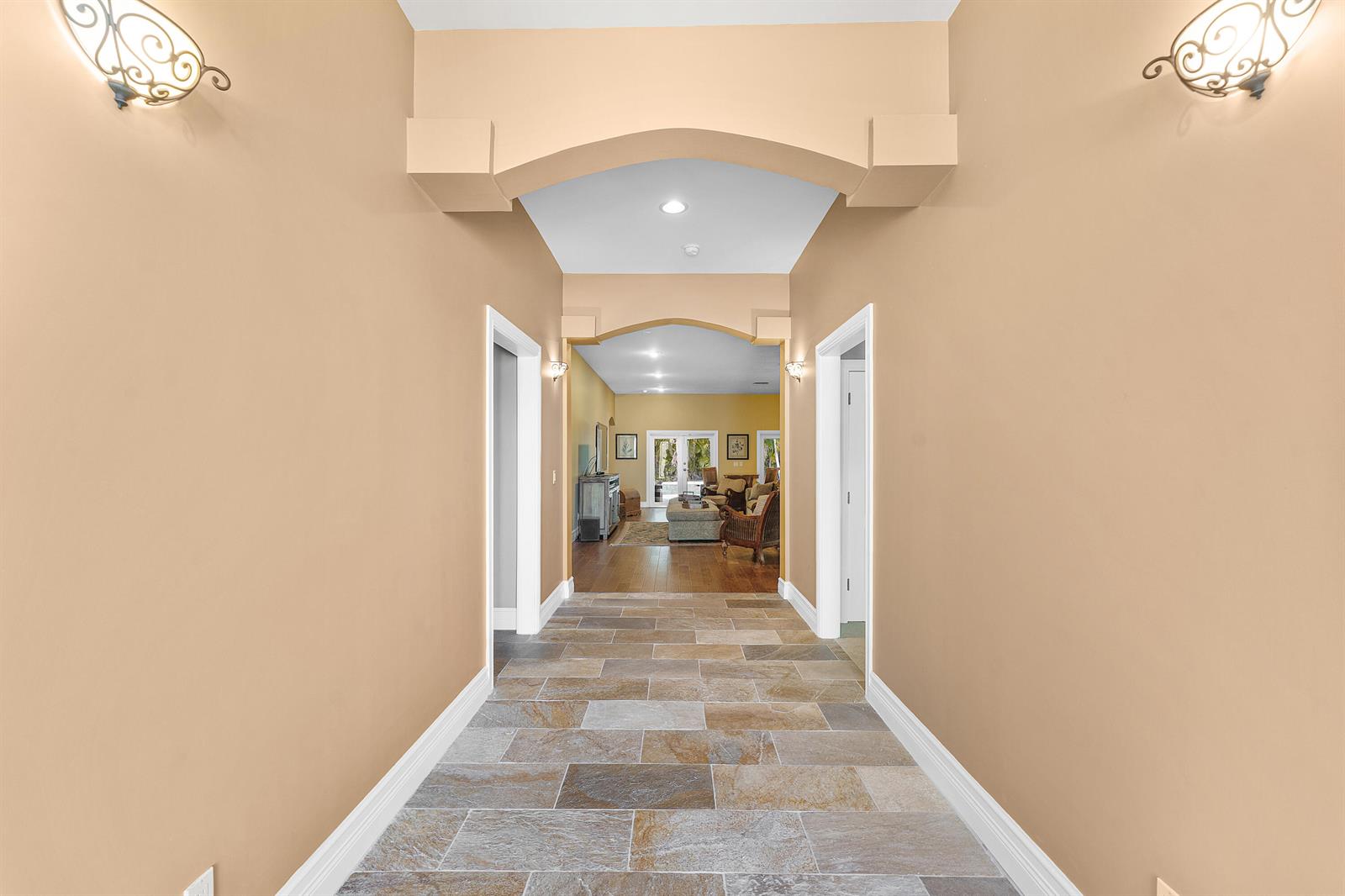 A hallway with stone tile flooring leads through arched doorways into a living area — 10295 Saint Andrews Road, Boynton Beach FL 33436, BOYNTON BEACH, FL