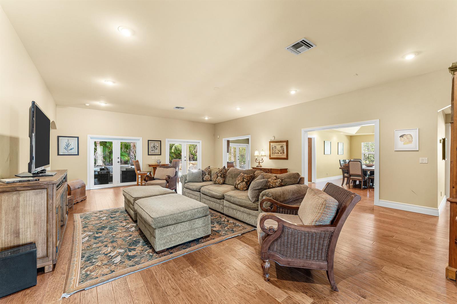 A living room features hardwood floors, a large sectional sofa, two ottomans, and glass doors — 10295 Saint Andrews Road, Boynton Beach FL 33436, BOYNTON BEACH, FL