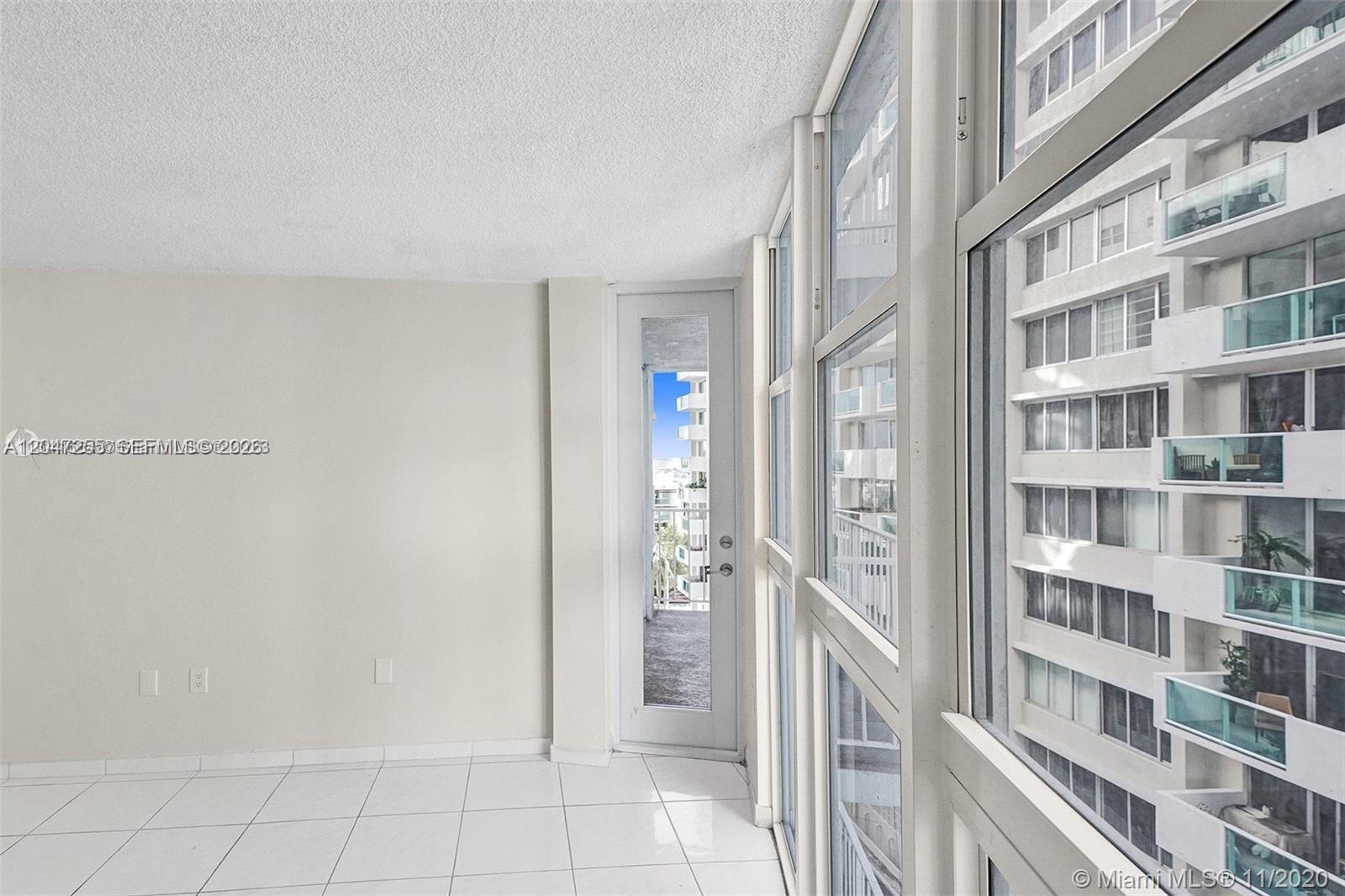 A room with white tile floors, a glass door to a balcony, and large windows — 1228 West Ave # 613, Miami Beach FL 33139, MIAMI BEACH, FL