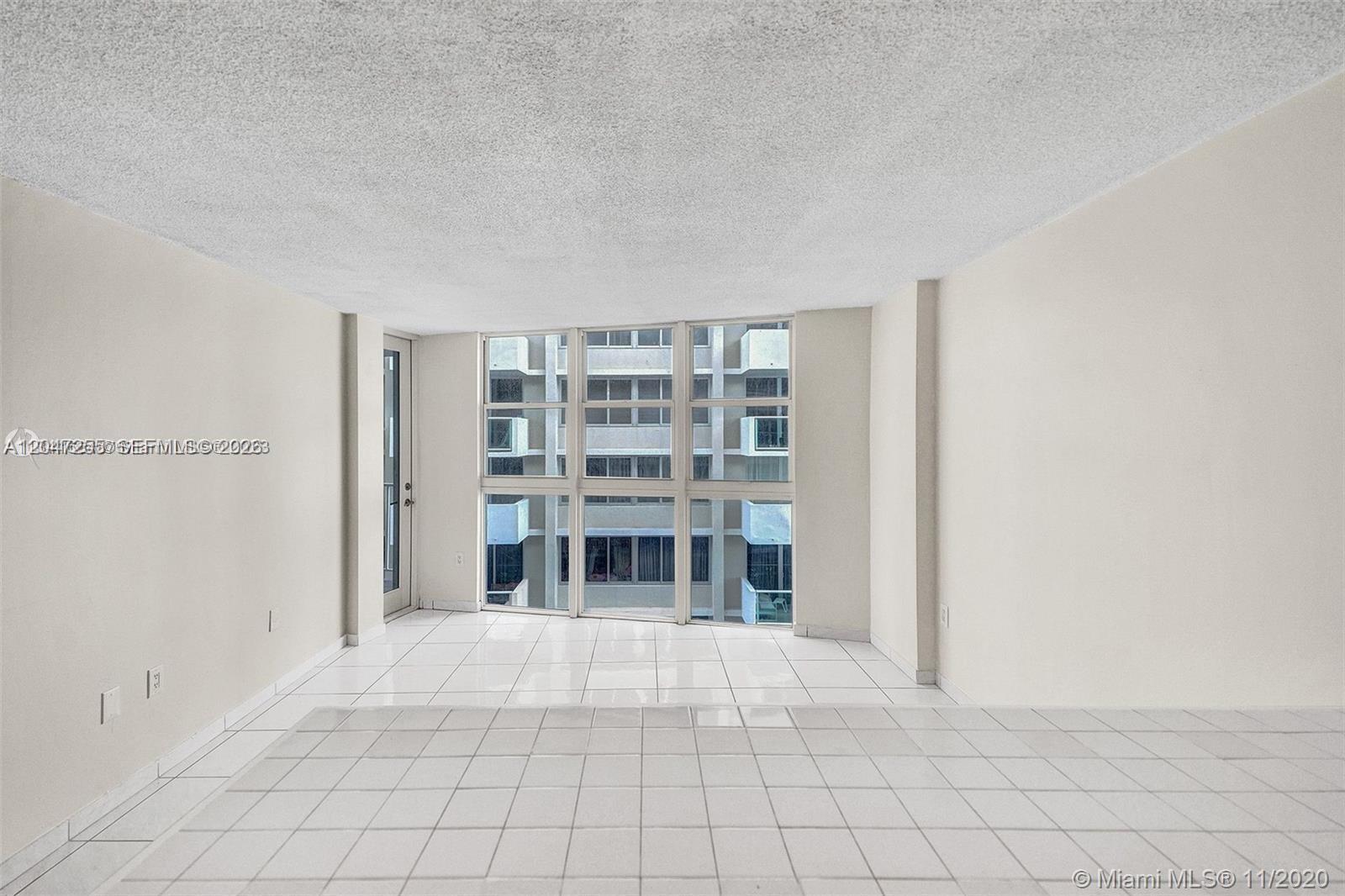 An empty room with white tile floors, plain walls, and a large window wall — 1228 West Ave # 613, Miami Beach FL 33139, MIAMI BEACH, FL
