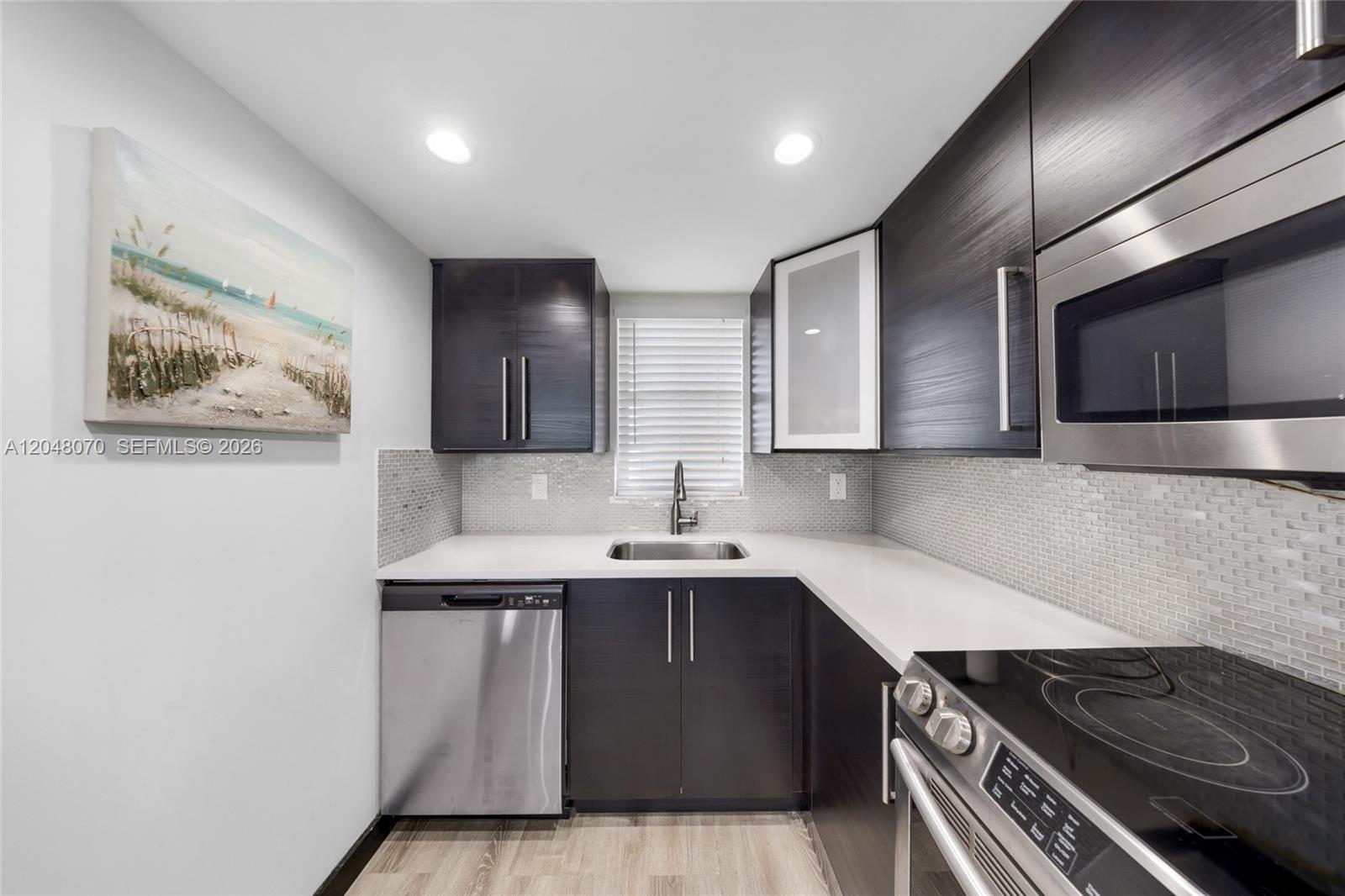 A modern kitchen features dark wood cabinets, stainless steel appliances, and a light-colored backsplash — 3001 W Rolling Hills Cir # 610, Davie FL 33328, DAVIE, FL