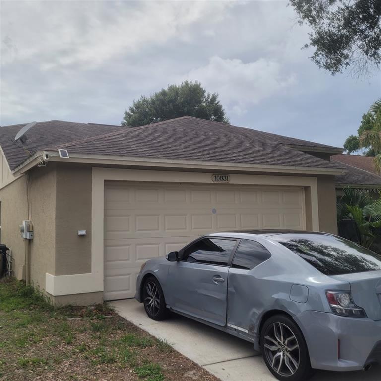 A light-colored house with a two-car garage and a grey car parked in the driveway — 10831 PEPPERSONG DRIVE, RIVERVIEW, FL