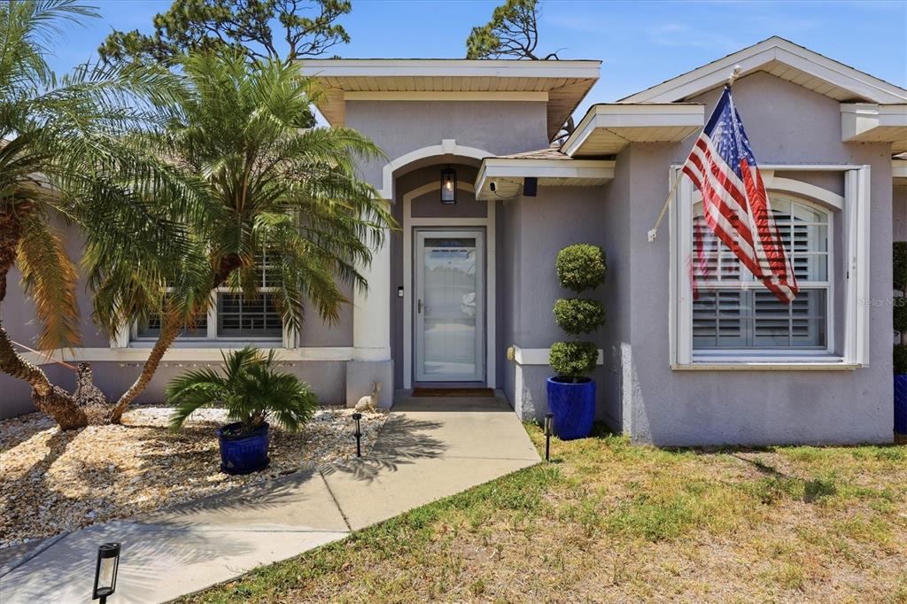 The exterior of a house features a palm tree, a front door, and an American flag — 5948 ORCHIS ROAD, VENICE, FL