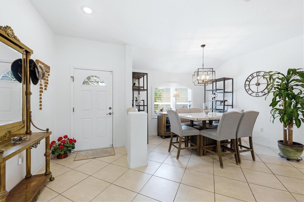 A dining area with a table and chairs sits near an entryway with tiled floors — 5948 ORCHIS ROAD, VENICE, FL