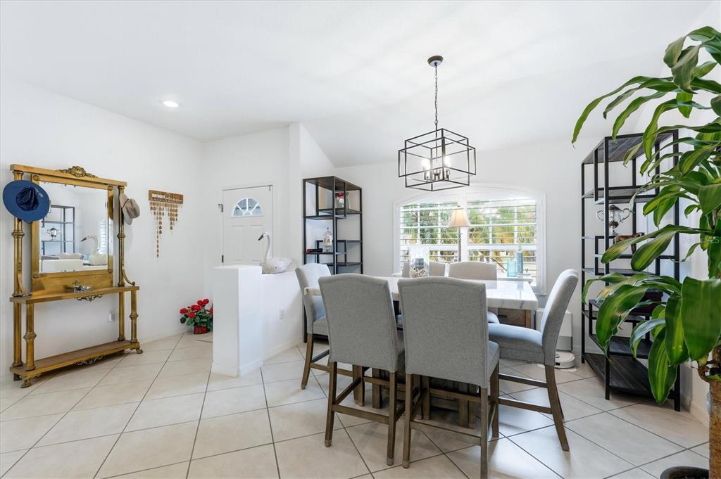 A dining room with a table, gray chairs, a chandelier, and a gold-framed mirror — 5948 ORCHIS ROAD, VENICE, FL