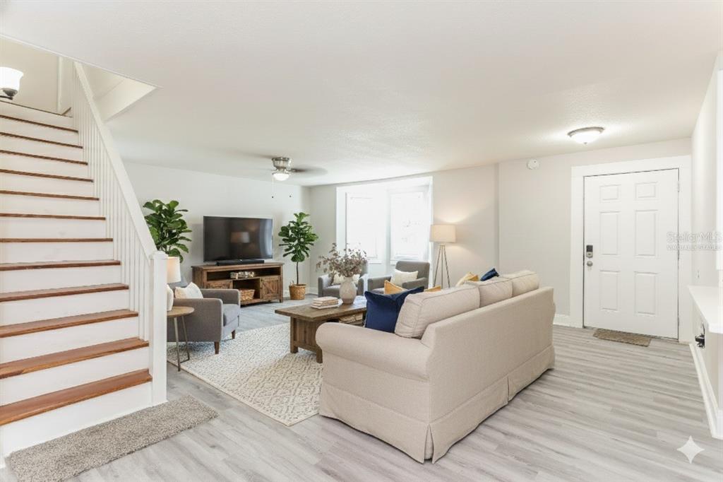 A living room features a staircase, light wood flooring, a sofa, and a television console — 4571 PARK STREET, JACKSONVILLE, FL