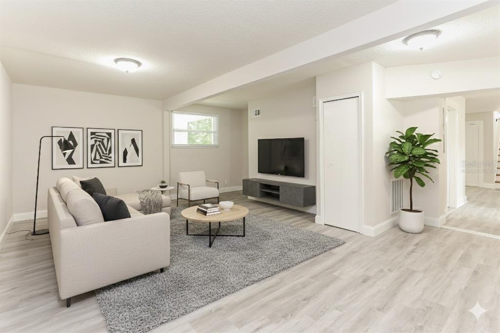 A living room with light wood-look flooring, a gray area rug, and a wall-mounted television — 4571 PARK STREET, JACKSONVILLE, FL
