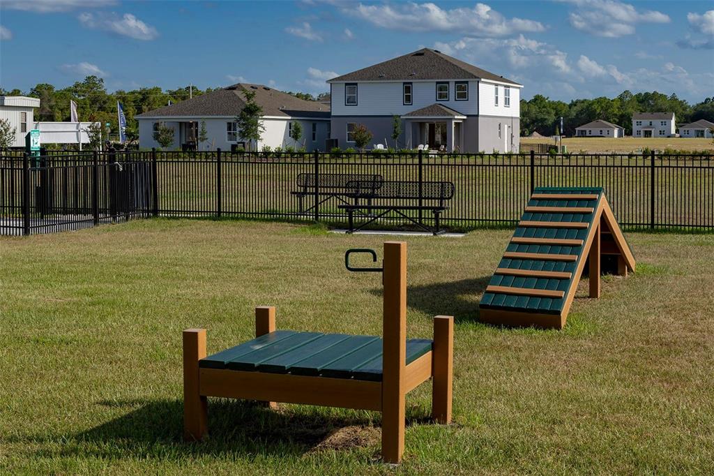 A fenced dog park features agility equipment, a bench, and nearby suburban houses — 2060 IORIO STREET, ST CLOUD, FL