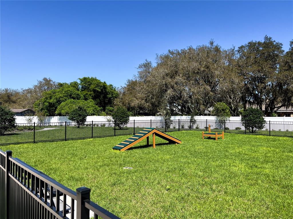A fenced-in dog park features a wooden A-frame ramp and a small hurdle on grass — 2060 IORIO STREET, ST CLOUD, FL