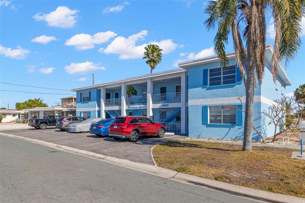 A two-story blue apartment building with a parking lot in front under a sunny sky — 11025 2ND STREET E UNIT 8, TREASURE ISLAND, FL