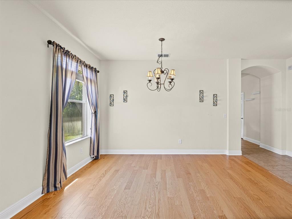 A dining room with hardwood floors, a chandelier, and a window with striped curtains — 11448 MERGANSER WAY, NEW PORT RICHEY, FL