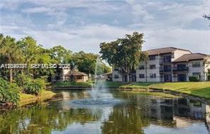 A multi-story apartment building sits behind a pond with a central water fountain — 9938 Nob Hill Pl # 1838, Sunrise FL 33351, SUNRISE, FL
