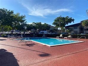 A rectangular swimming pool is surrounded by a red deck with lounge chairs and trees — 9938 Nob Hill Pl # 1838, Sunrise FL 33351, SUNRISE, FL