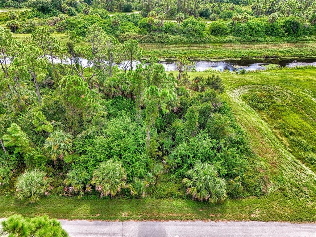 An aerial view of a wooded lot bordering a canal and a paved road — BARCELONA DRIVE, NORTH PORT, FL