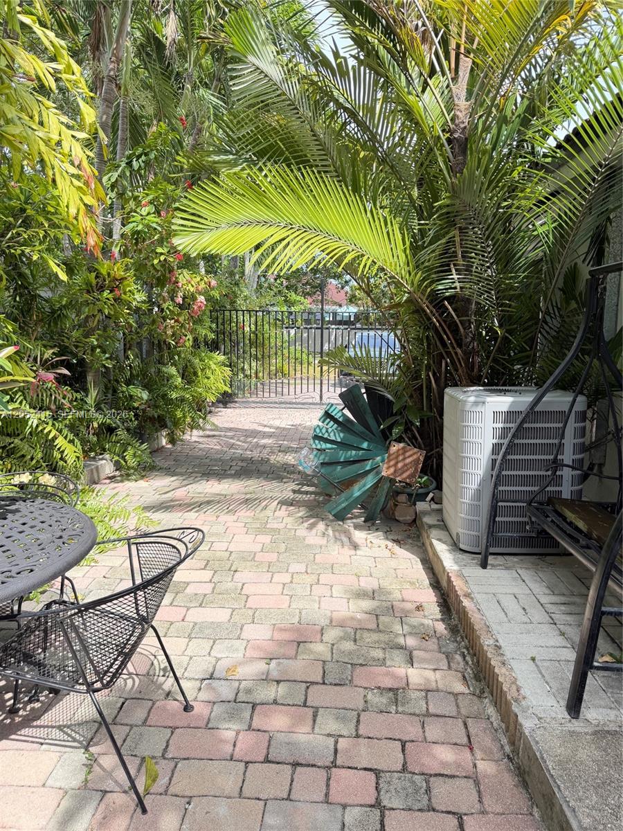 A paved patio area features a metal table, chairs, a swing, and lush tropical landscaping — 21920 Old Cutler Rd # 0, Cutler Bay FL 33190, CUTLER BAY, FL