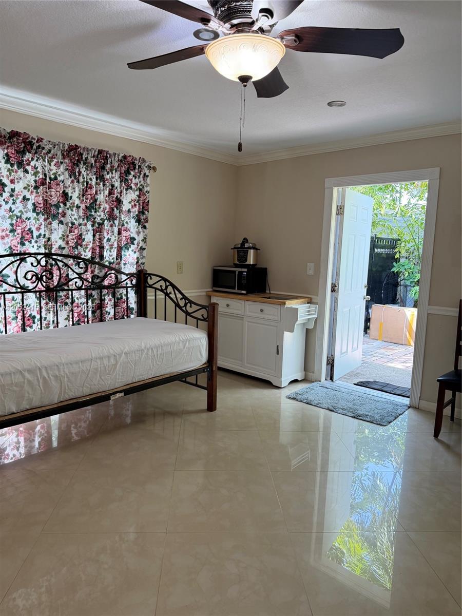 A bedroom features a metal daybed, a small kitchen island with appliances, and an open door — 21920 Old Cutler Rd # 0, Cutler Bay FL 33190, CUTLER BAY, FL