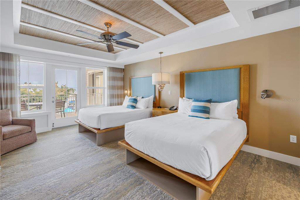 A hotel room features two queen beds with blue headboards and a textured ceiling — 5325 MARINA DRIVE UNIT 128, BRADENTON BEACH, FL