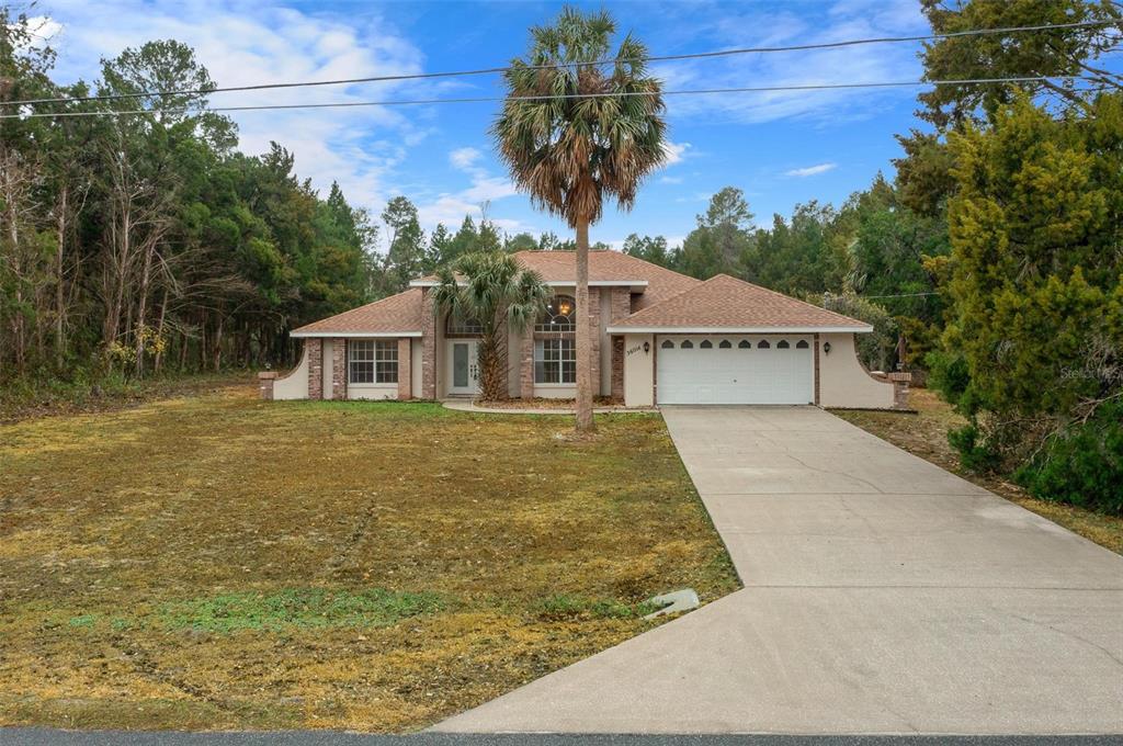 A single-story house with a tan exterior, a two-car garage, and a palm tree out front — 36014 LAKE UNITY NURSERY ROAD, FRUITLAND PARK, FL