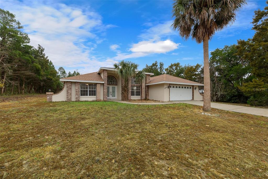A single-story house with a beige exterior, brick accents, and a two-car garage — 36014 LAKE UNITY NURSERY ROAD, FRUITLAND PARK, FL