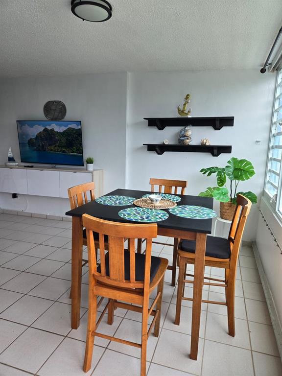 A dining area features a square black table with four wooden chairs on tiled flooring — 100 AVENIDA MARINA VIEW DOS MARINAS CONDOMINIUM UNIT 303, FAJARDO, PR