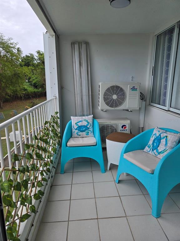 A balcony features two blue chairs with crab pillows, a small table, and air conditioning units — 100 AVENIDA MARINA VIEW DOS MARINAS CONDOMINIUM UNIT 303, FAJARDO, PR