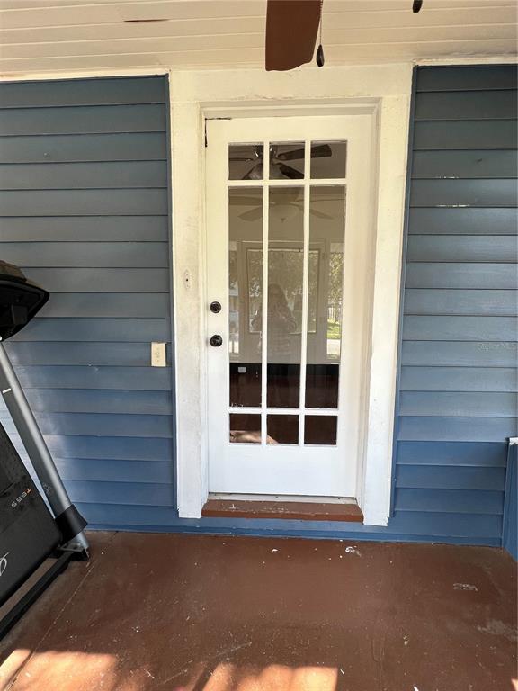 A white French door with glass panes is set into a blue-sided exterior wall — 505 WASHINGTON AVENUE, EUSTIS, FL