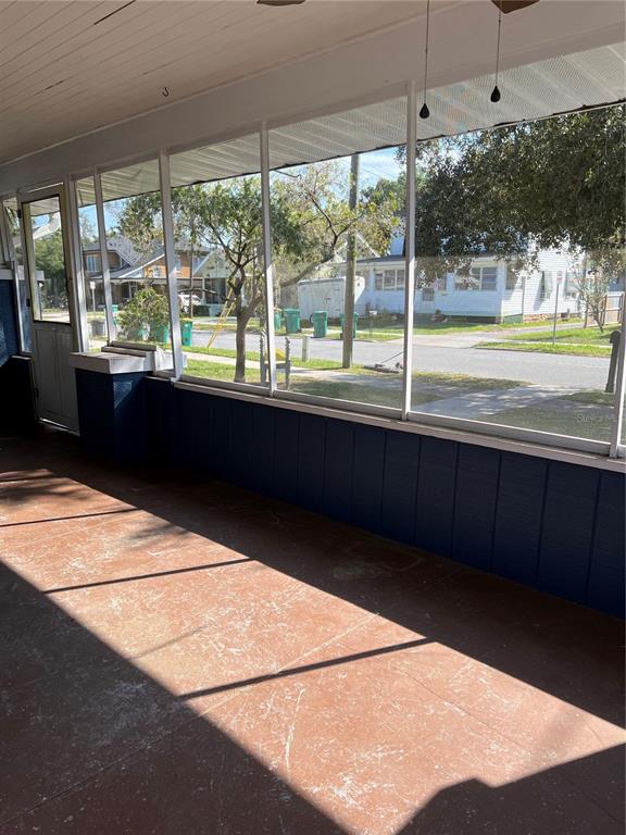 A screened-in porch with a painted concrete floor and dark blue wood paneling — 505 WASHINGTON AVENUE, EUSTIS, FL