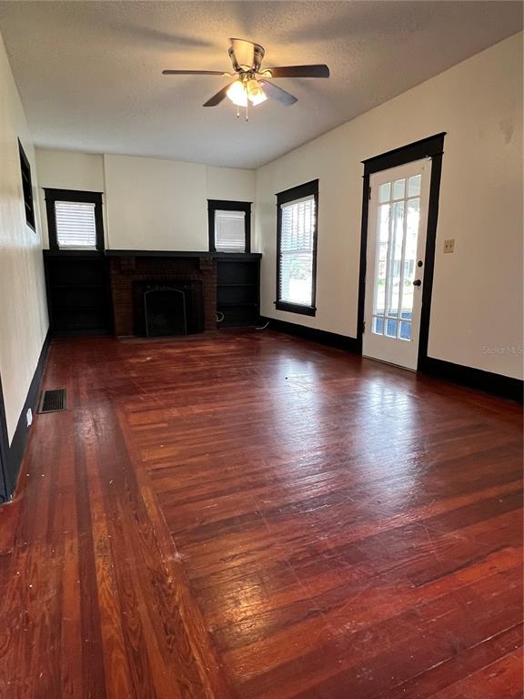 A living room features hardwood floors, a brick fireplace, built-in shelves, and a ceiling fan — 505 WASHINGTON AVENUE, EUSTIS, FL