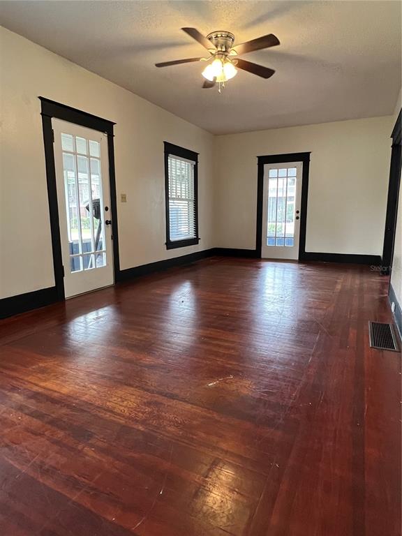 A room with hardwood floors, a ceiling fan, and two glass-paned doors with black trim — 505 WASHINGTON AVENUE, EUSTIS, FL